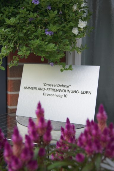 Eingangsschild an der Haustür: Aluschild mit der Aufschrift "Drossel deluxe, Ammerland-Ferienwohnung-Eden, Drosselweg 10"