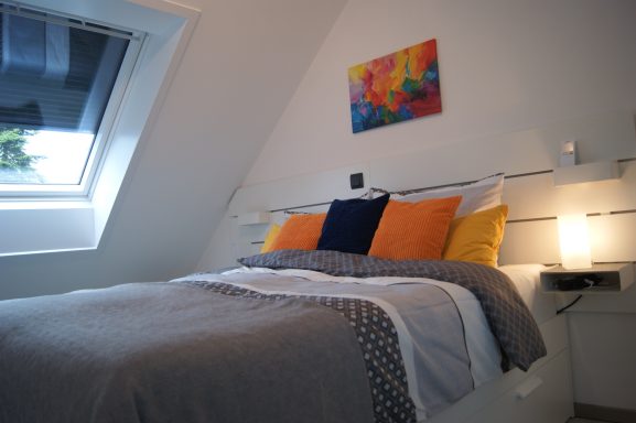 Blick auf das Bett des frisch bezogenen Schlafzimmer 2 mit Nachttischlampen