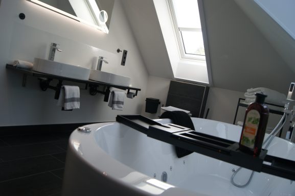Die helle Whirlwanne in der Ferienwohnung. Im Vordergrund ein dunkles Handtuch.