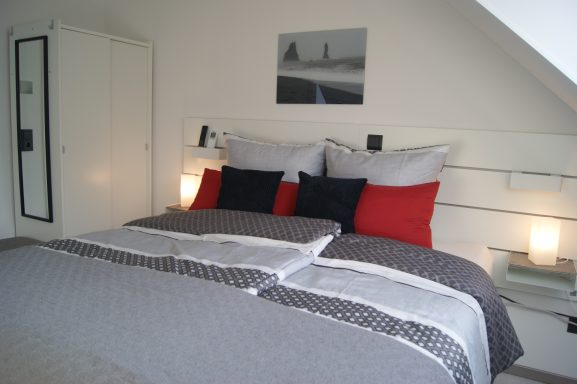 Blick auf das Bett des frisch bezogenen Schlafzimmer 1 mit Nachttischlampen