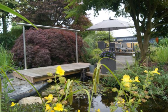 Blick auf die kleine Brücke am Gartenteich, die zur Terrasse der Ferienwohnung führt.