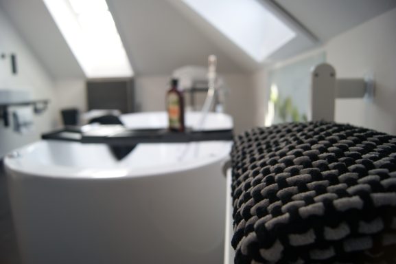 Die helle Whirlwanne in der Ferienwohnung. Im Vordergrund ein dunkles Handtuch.